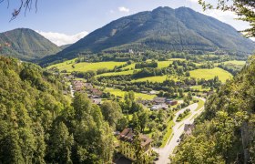 Panoramic view of a green valley with mountains in the background and a village in the foreground.
