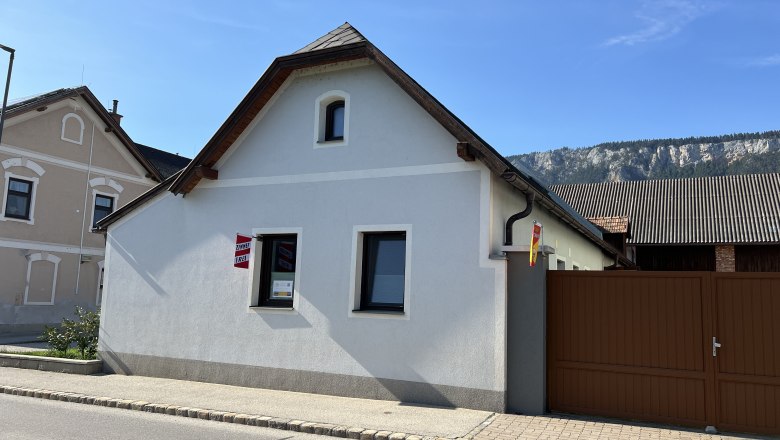 Vacation cottage Höflein, © Anton Sommer A small, white vacation home with a brown gate and a mountain backdrop.