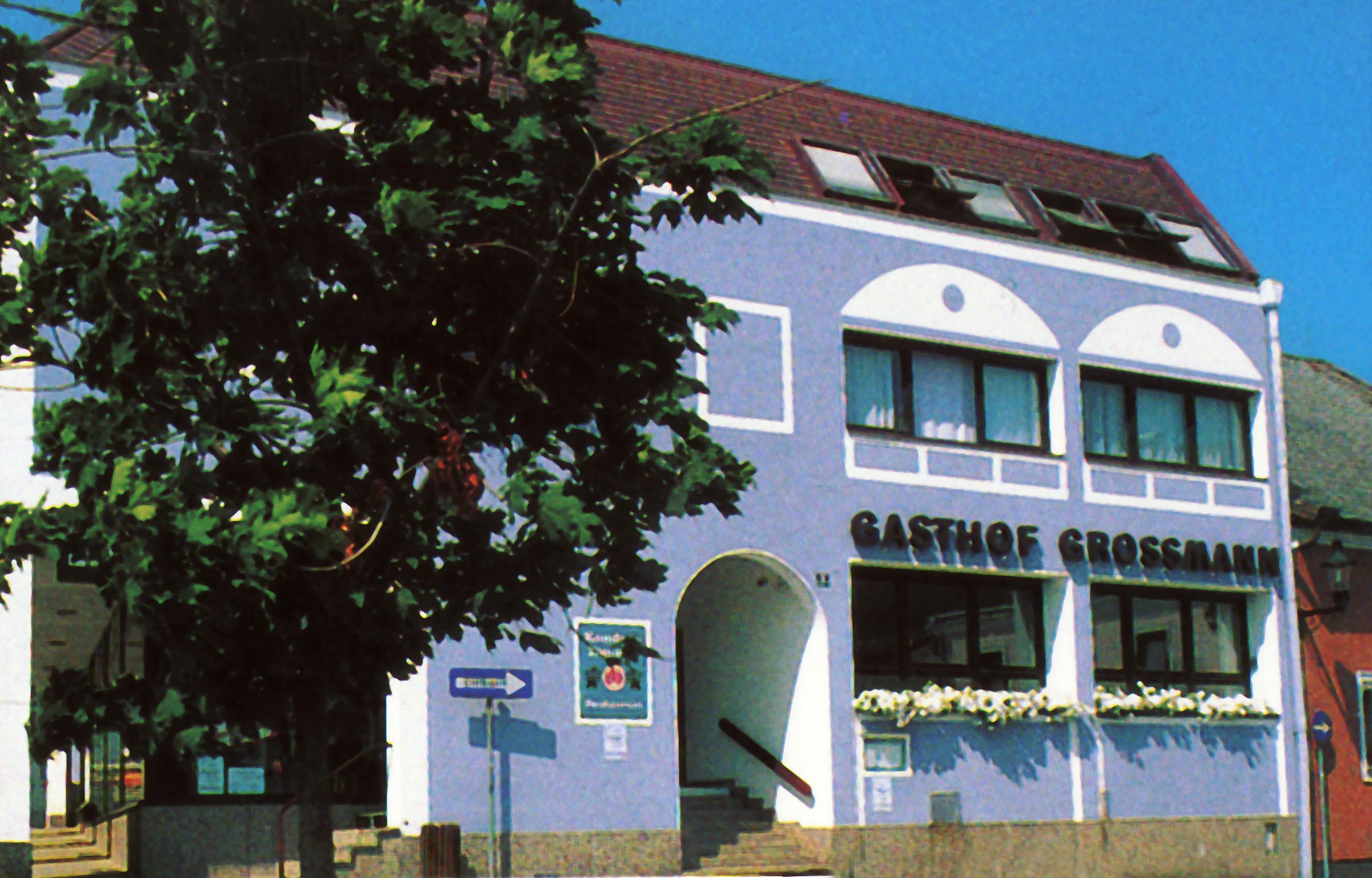 Gasthof Großmann with blue façade and tree in the foreground.