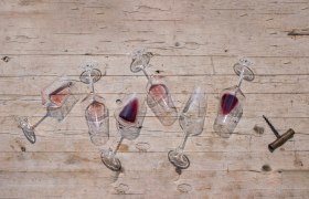 Overturned wine glasses with red wine on a wooden table.