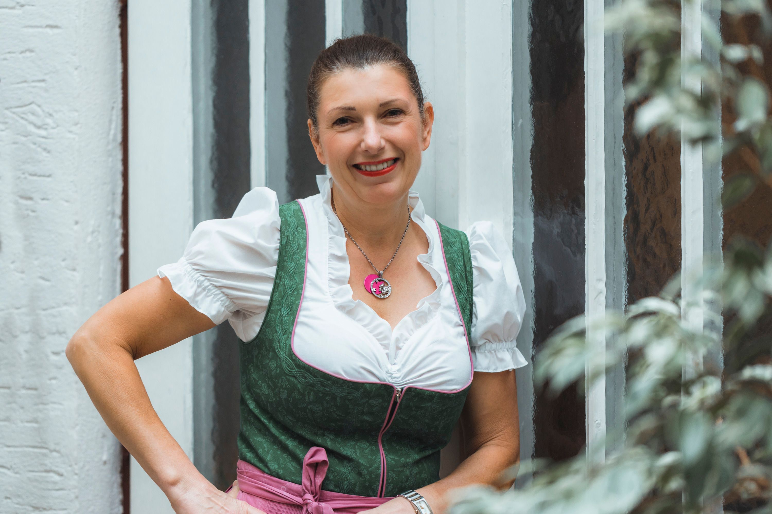 Woman in traditional costume in front of a wall with stained glass windows.