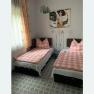 Two single beds with pink and white checkered comforters in a bedroom with a patterned floor and a picture on the wall.
