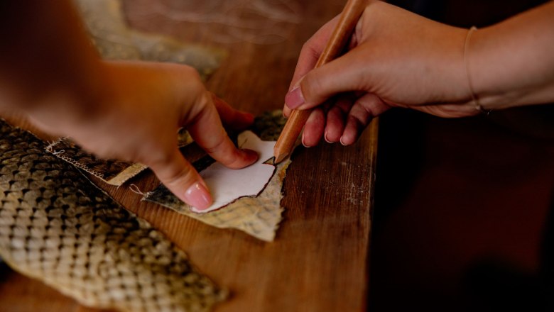 Close-up of hands drawing a stencil on fish leather.