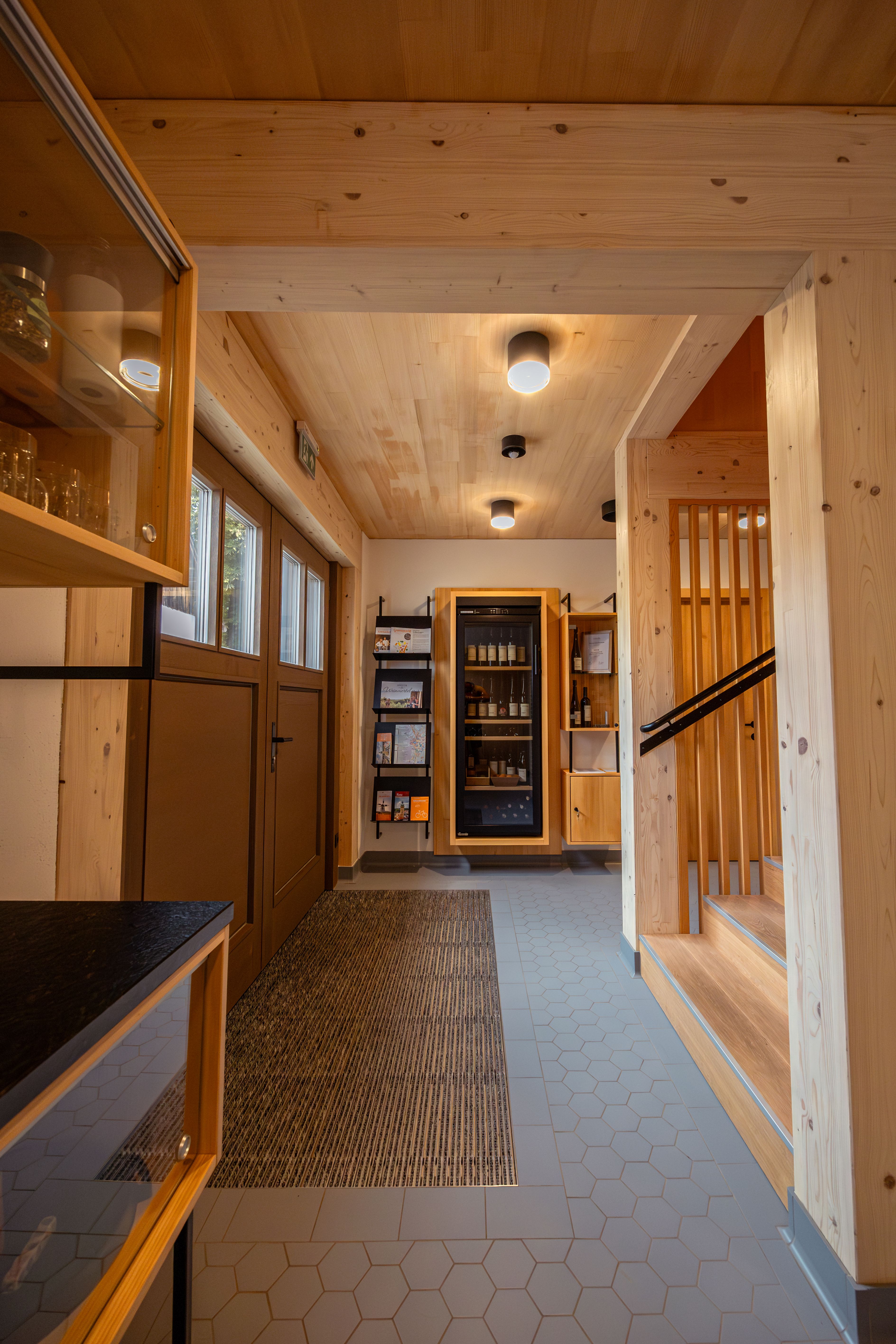 A modern Kellerstöckl in the Weinviertel at dusk, surrounded by vines and a garden. A sign shows 'vacation on a farm'.