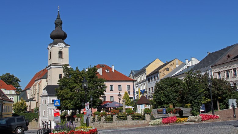 Town square in Heidenreichstein with church and colorful flower beds.