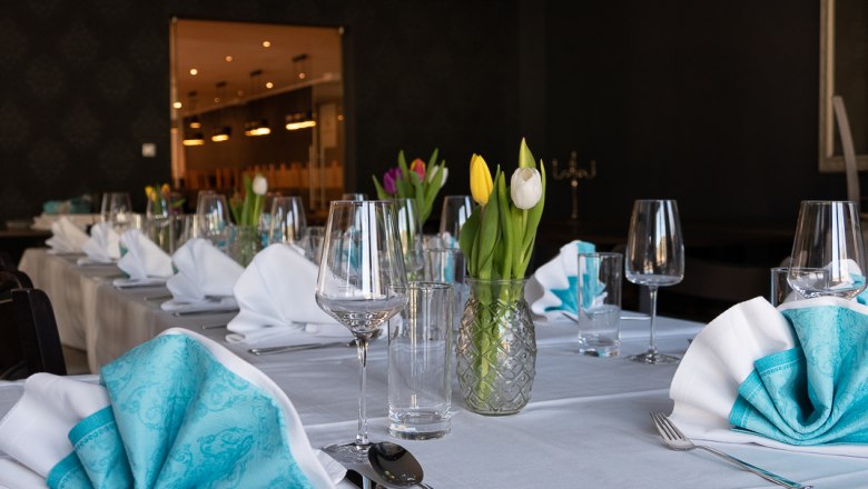 Elegant table with white tablecloths, turquoise napkins and tulips in vases.