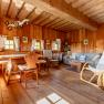 Dining area with wooden furniture, rocking chair and sofa in a room with wood paneling.