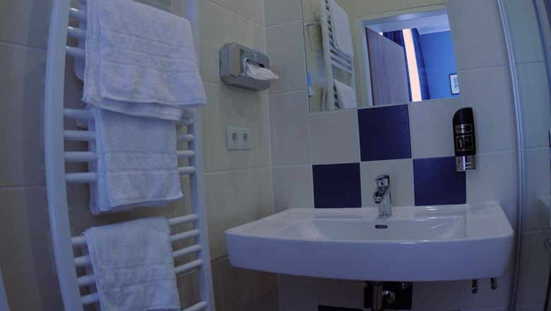 Modern bathroom with blue and white tiles, washbasin, towel rail and mirror.
