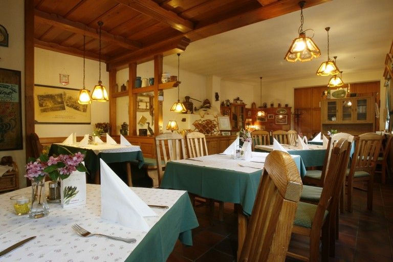 Interior view of a cozy inn with wooden furniture and laid tables.