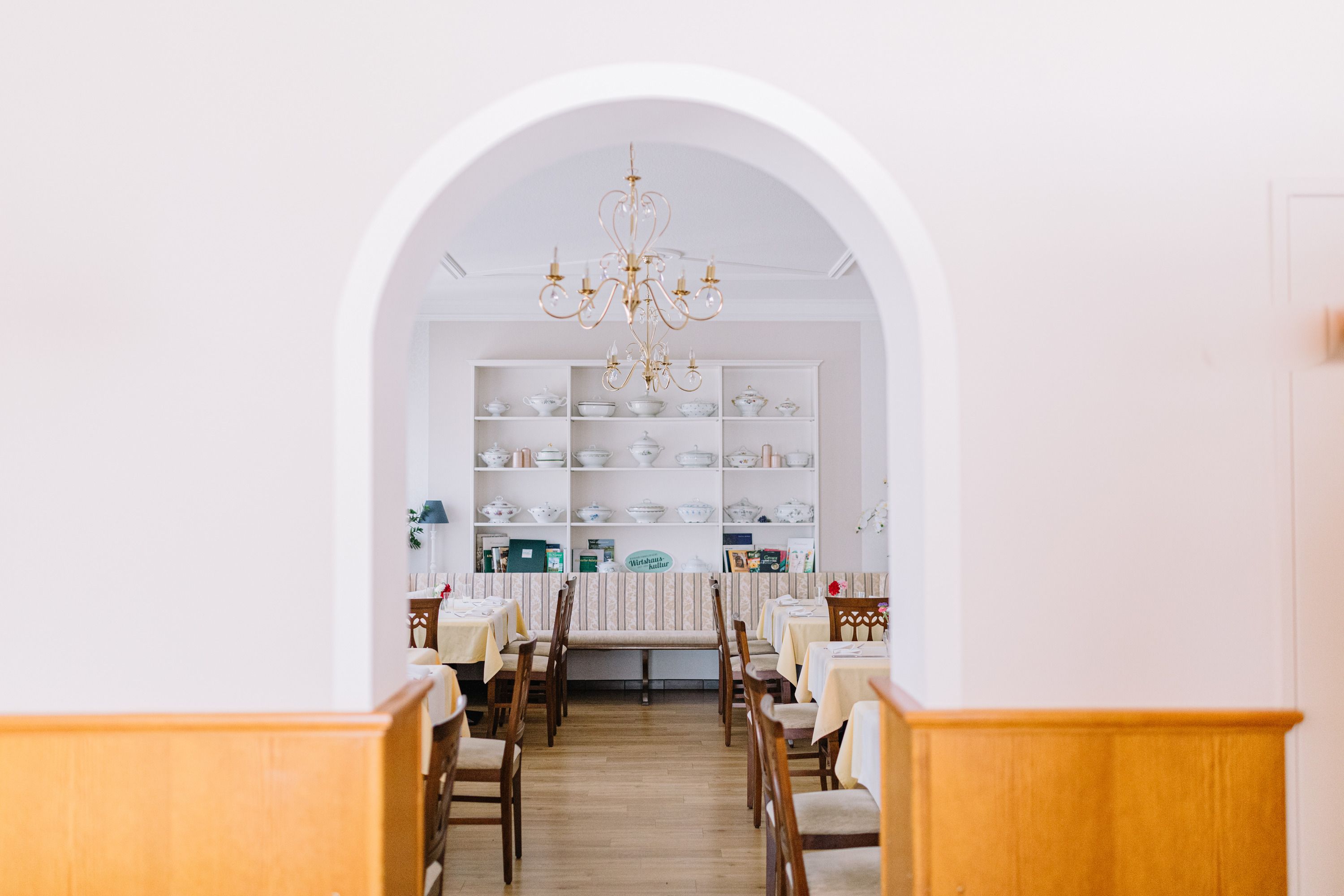 Interior view of a traditional inn with set tables and a chandelier.