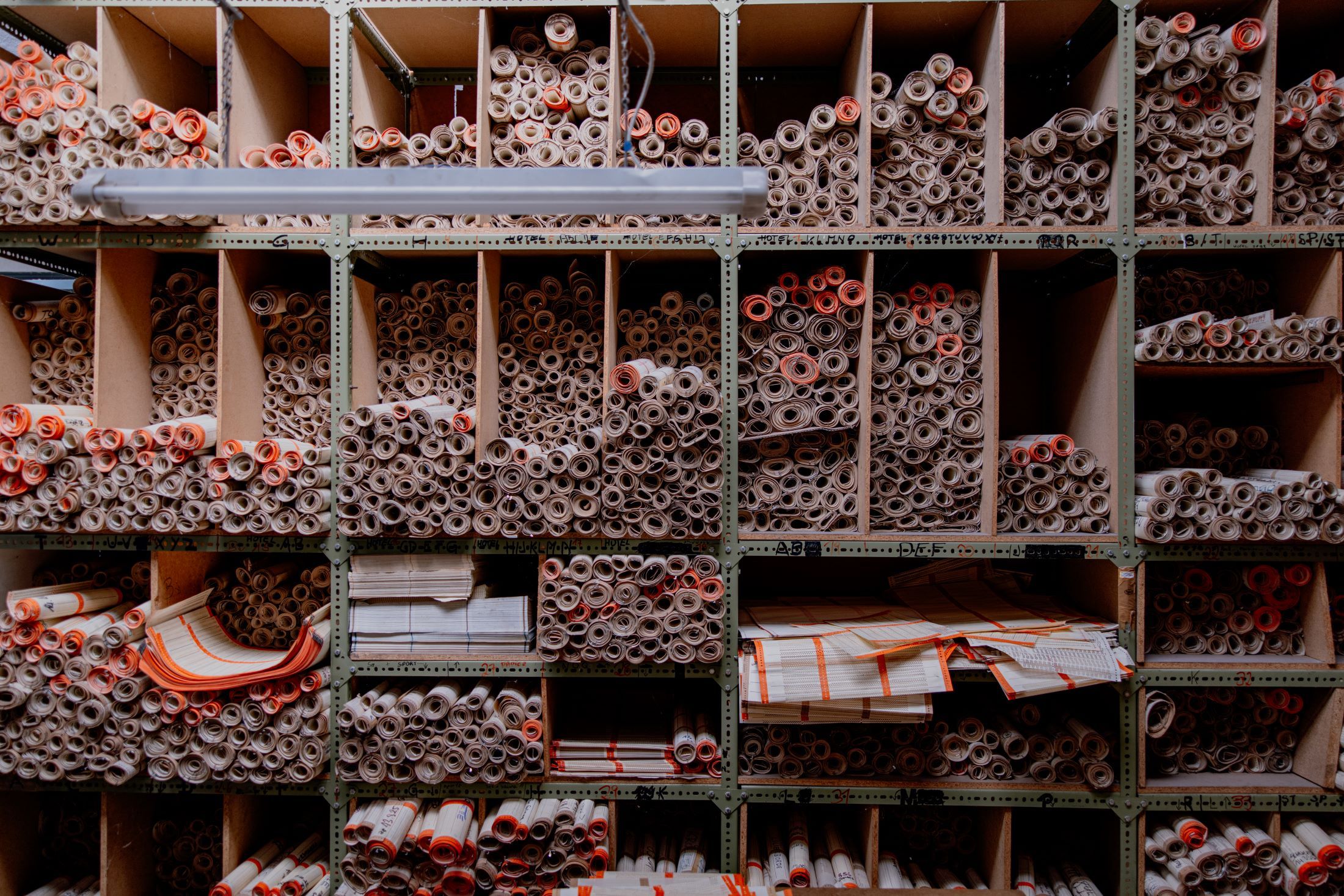 Shelf with many rolled paper documents in compartments.