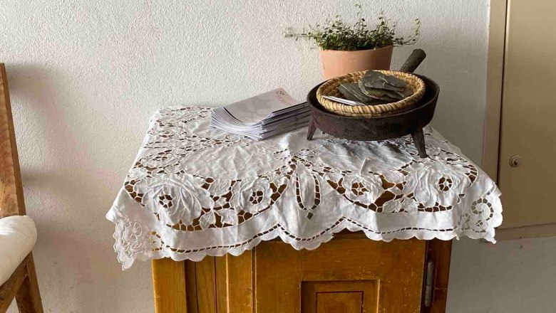Detail in the living area, © Familie Stagard A small wooden table with a lace ceiling, plants and a framed picture on the wall.