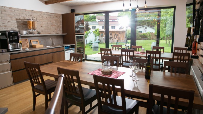 Interior view of a modern dining room with wooden tables and chairs, large windows and a view of a garden.