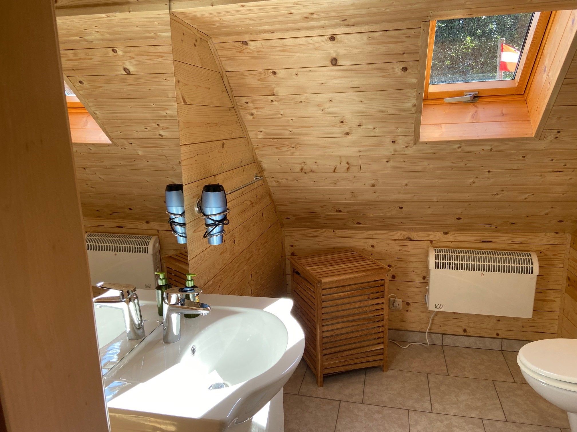 Wood-paneled bathroom with washbasin, mirror, skylight and radiator.