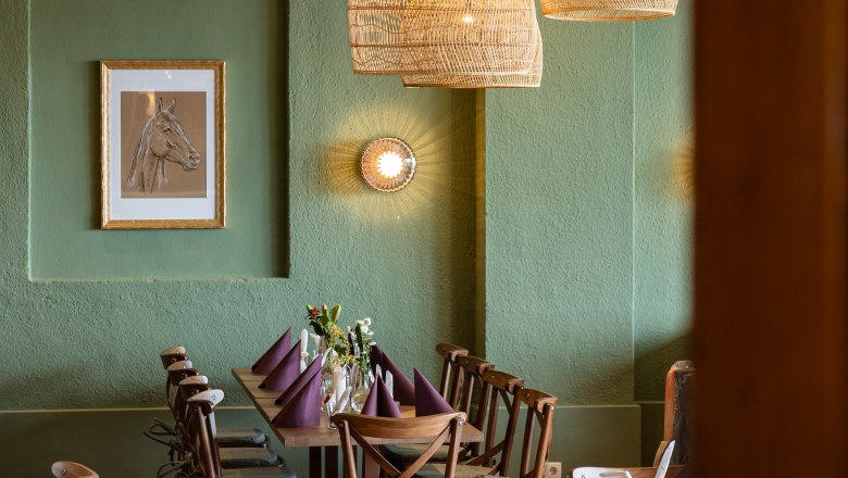 Cozy dining area with wooden table, chairs and woven lamps.