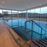 Interior view of a modern indoor pool with large windows and a view of nature.