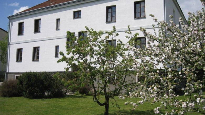 Gasthof-Apartement Schreiber-Zalto, © Gasthof-Apartement Schreiber-Zalto A white building with a brown roof and blossoming trees in the foreground.