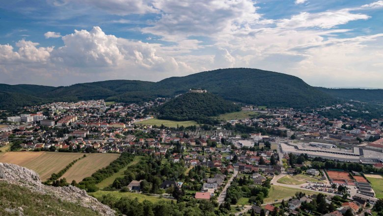 Panoramic view of a city with hills in the background and a cloudy sky.