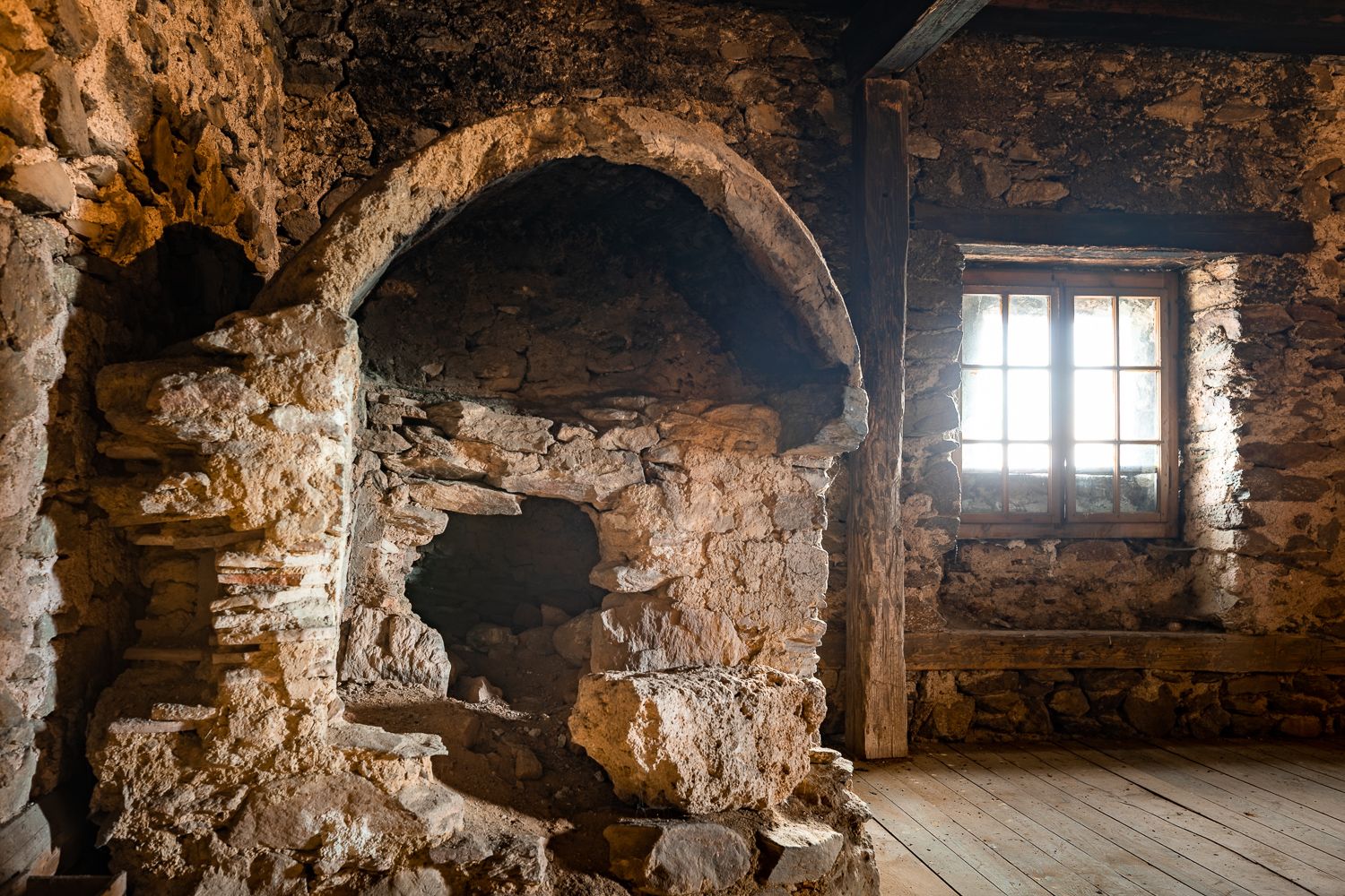 Old oven in a stone room with wooden floor and window. Located in the attic of the Lichtenegg fortified church.