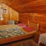 Wood-paneled bedroom with double bed, colorful blankets and open window.