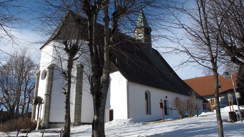 Maria Namen parish church in winter with snow-covered ground and bare trees.