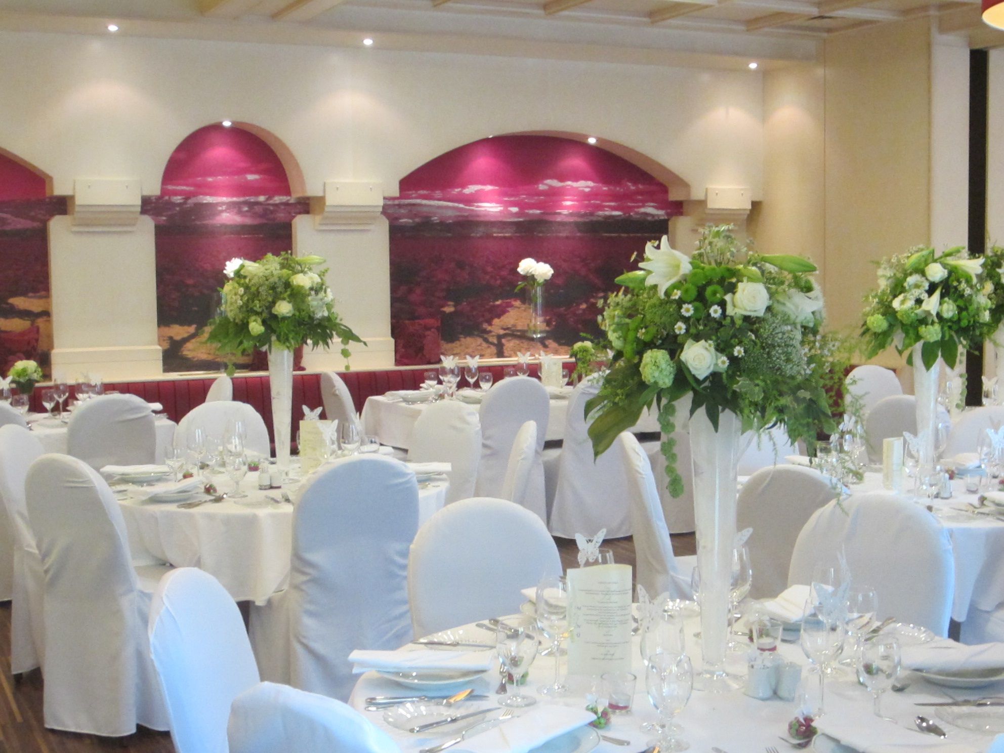 Elegant banquet hall with white-clothed tables and flower arrangements.