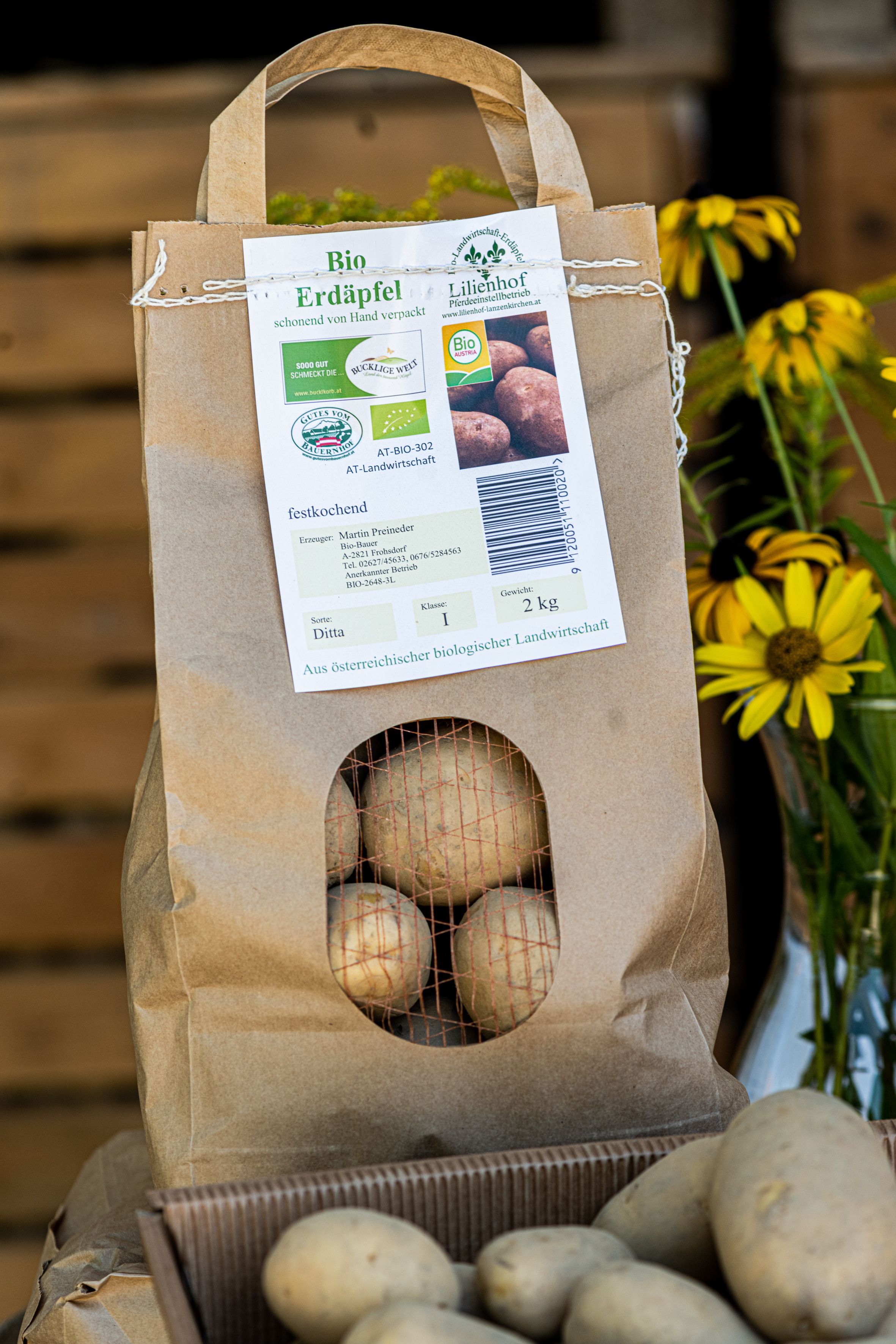 A paper sack of organic potatoes with yellow flowers next to it.