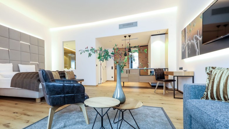 Modern furnished hotel room with bed, armchairs, table and decoration.