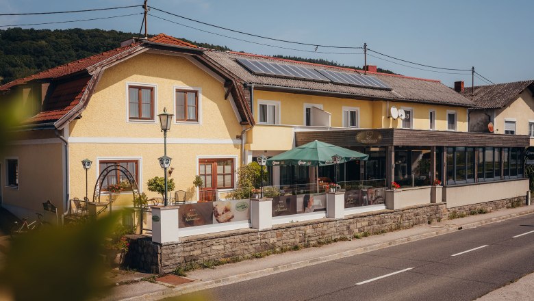 Yellow inn with terrace and parasols on a country road.