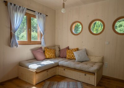 Cozy sitting area in a wooden modular house with round windows.