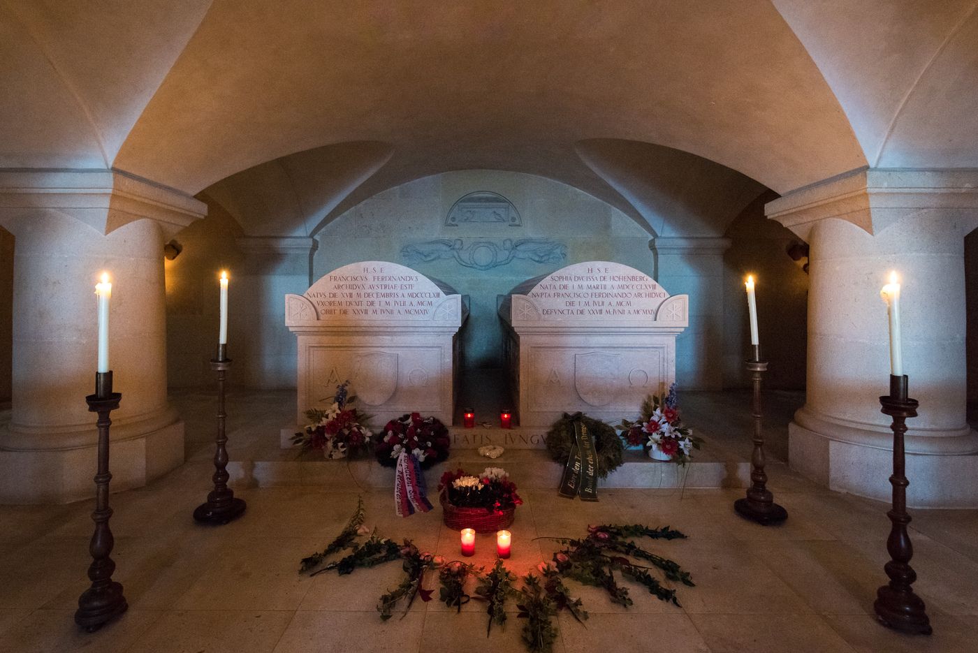 Interior view of a family tomb with two gravestones, candles and flowers.