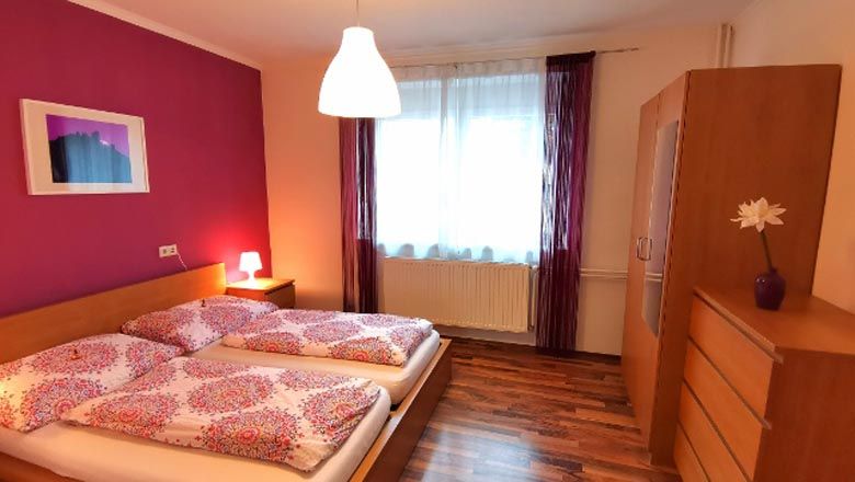 Cozy bedroom with double bed, pink wall and wooden furniture.