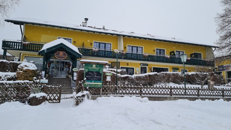 Krumbacherhof, © Wiener Alpen / Cornelia Schuh Yellow building in the snow with green veranda and entrance.