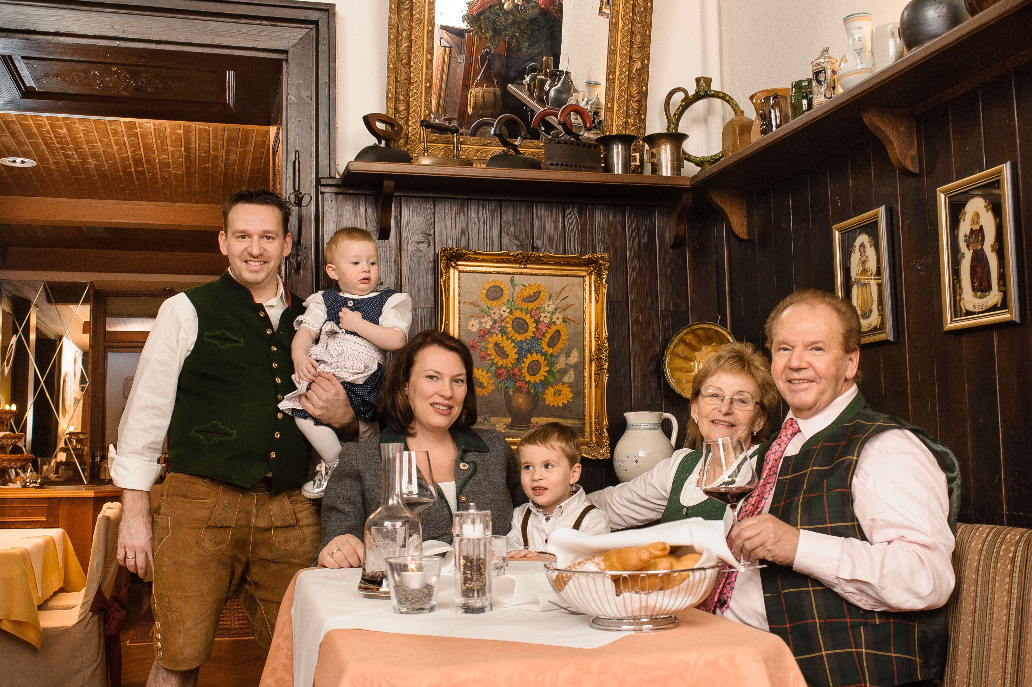 A family in traditional dress sits at a table in a rustic restaurant.