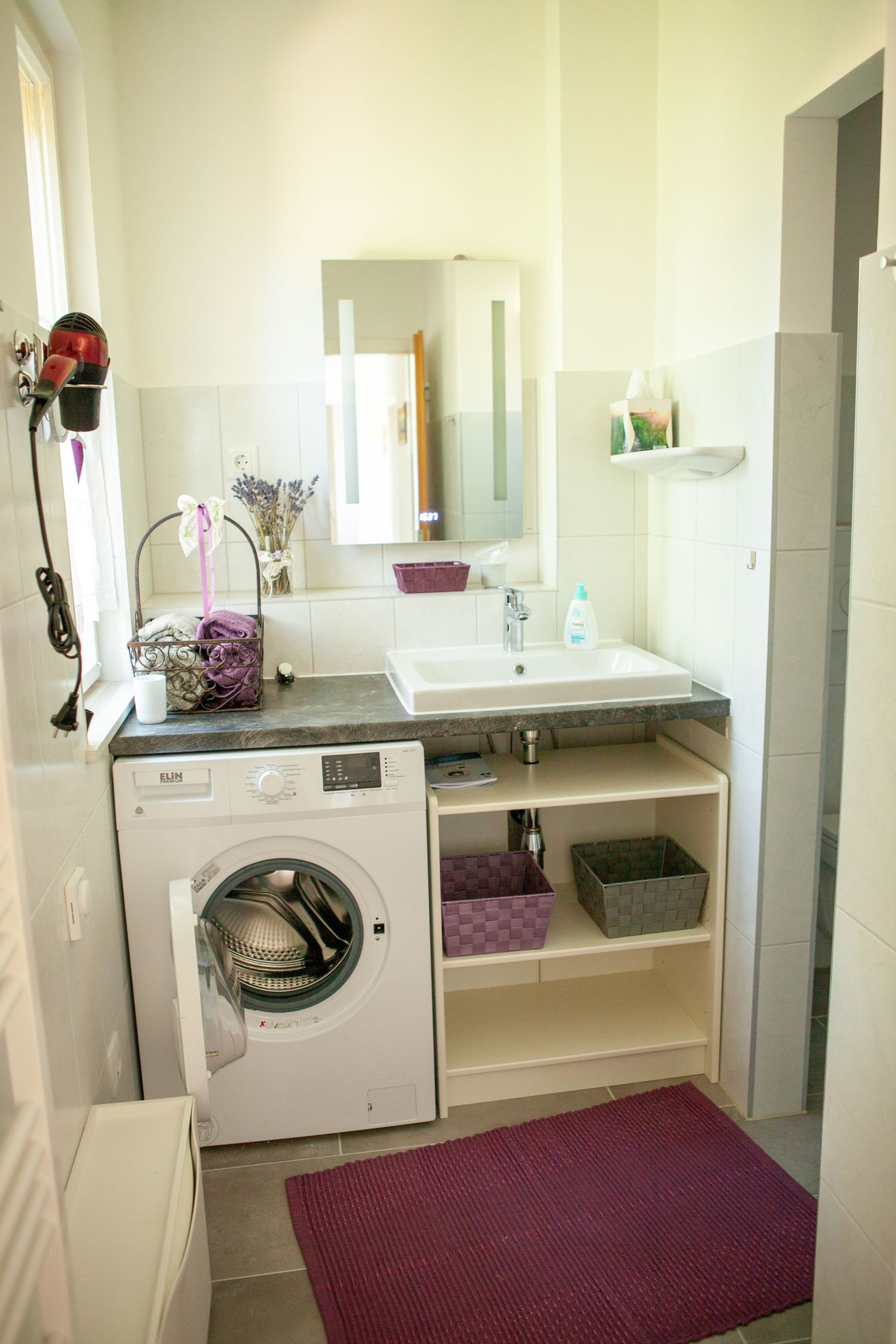 Modern bathroom with washing machine, washbasin and mirror.