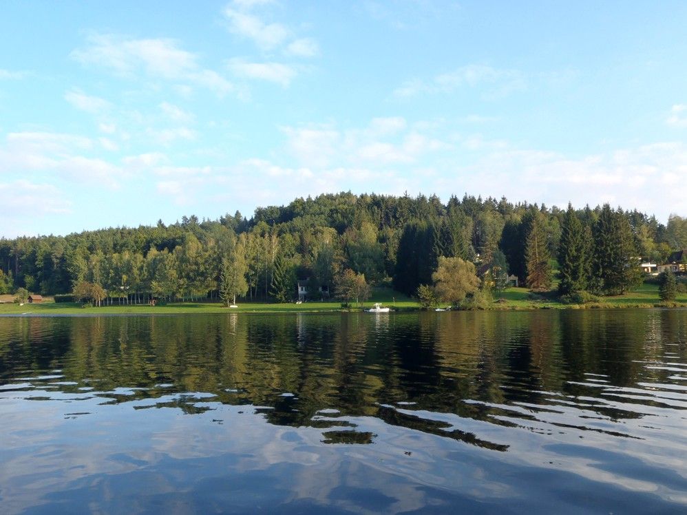View of the Thurnberg reservoir with wooded shore and clear sky.