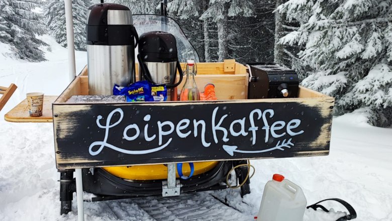 Mobile coffee stand in the snow with the inscription 'Loipenkaffee'.