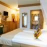 Comfortable hotel room with double bed, wooden furniture and small bathroom.