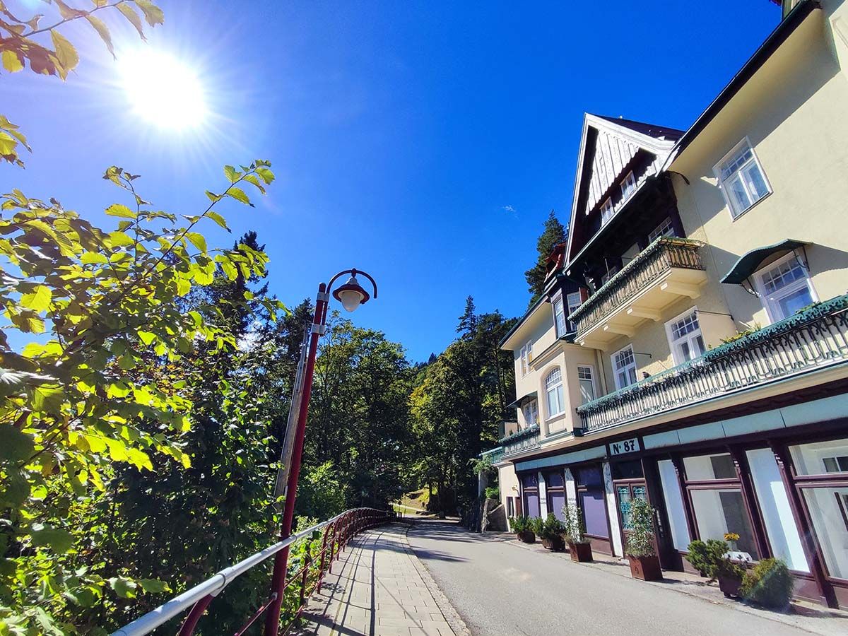 Sunny day in front of a villa with a balcony and trees.