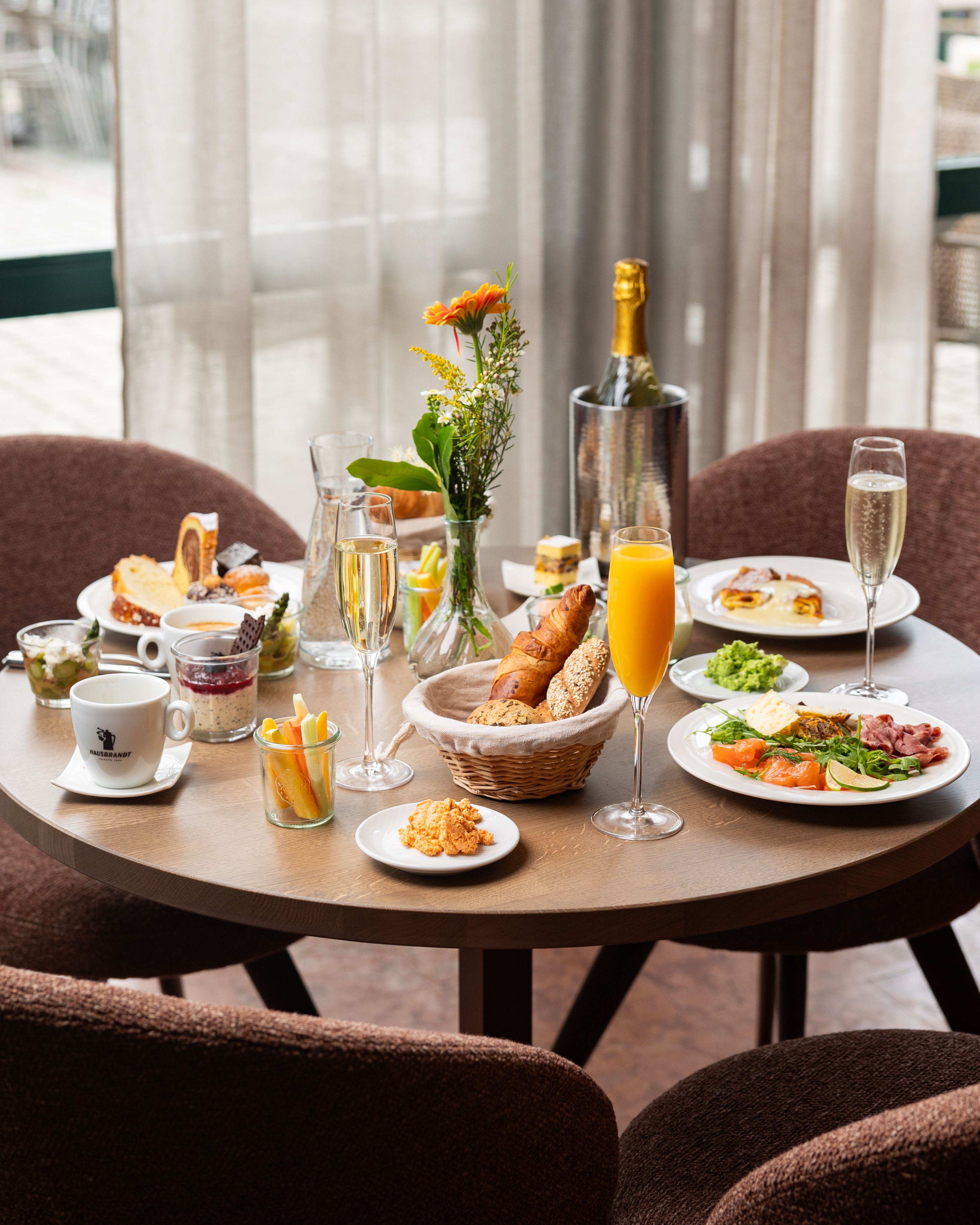 A laid breakfast table with various dishes, drinks and flowers.