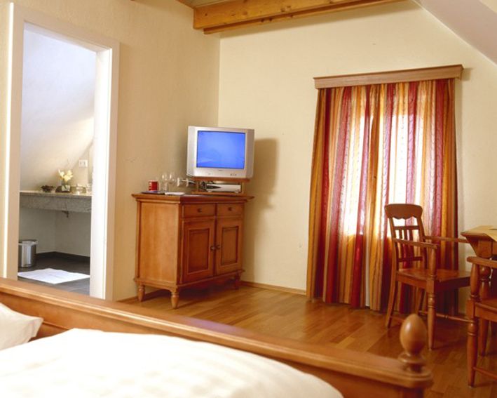 Cozy room with wooden furniture, TV and colorful curtains.