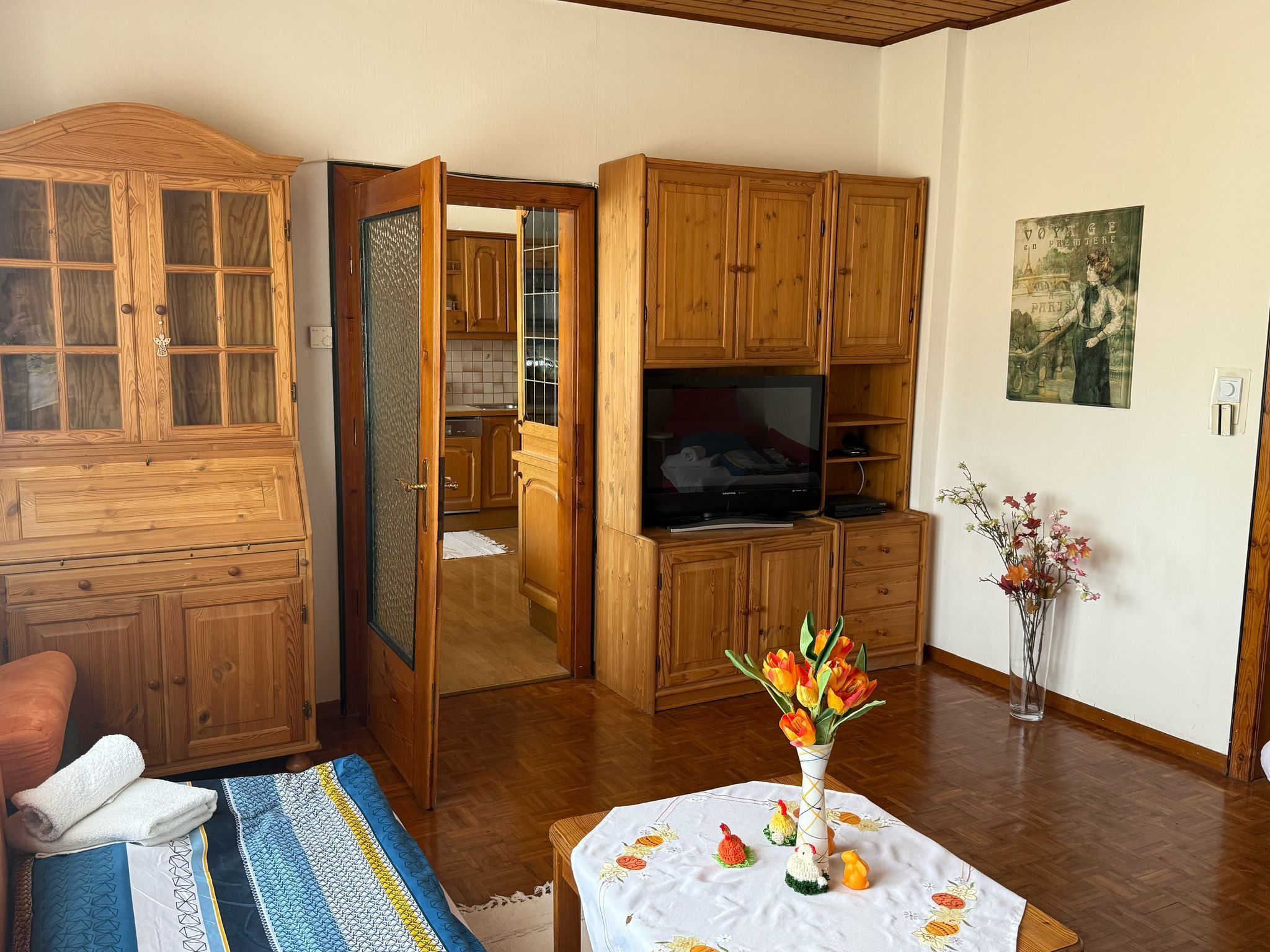 Living room with wooden furniture, a table with flowers and a TV.