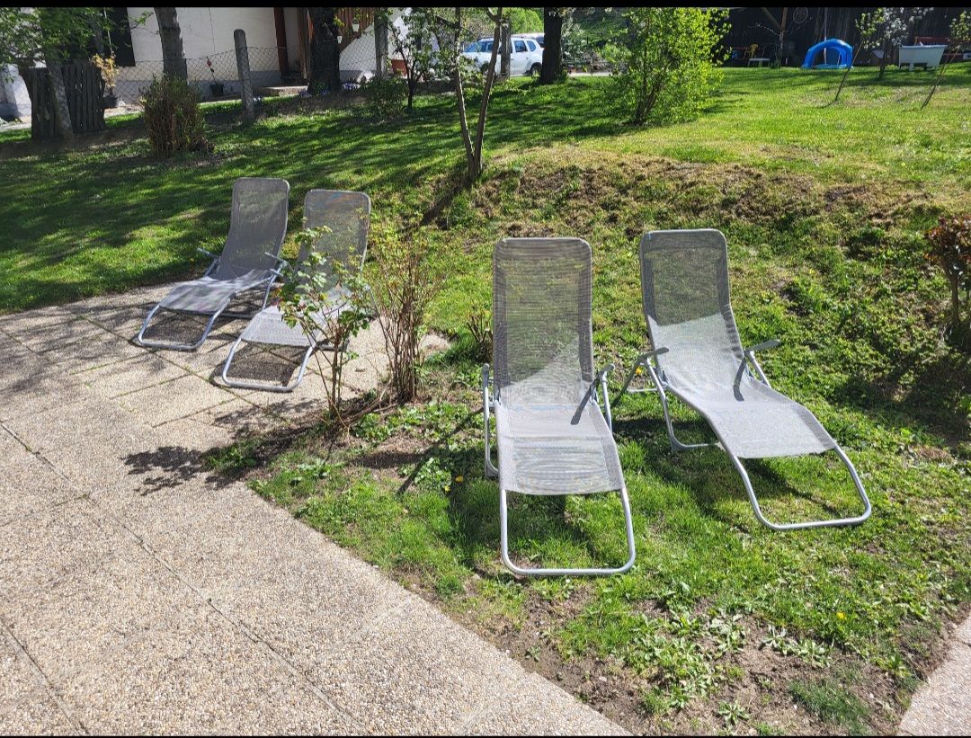 Four sun loungers on a terrace in the garden.