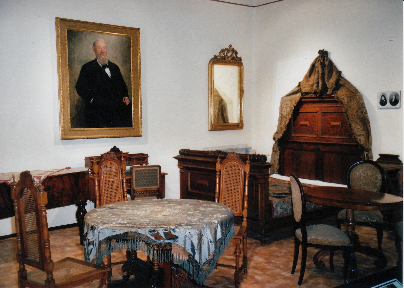Historic room with antique furniture and a painting of a man on the wall.