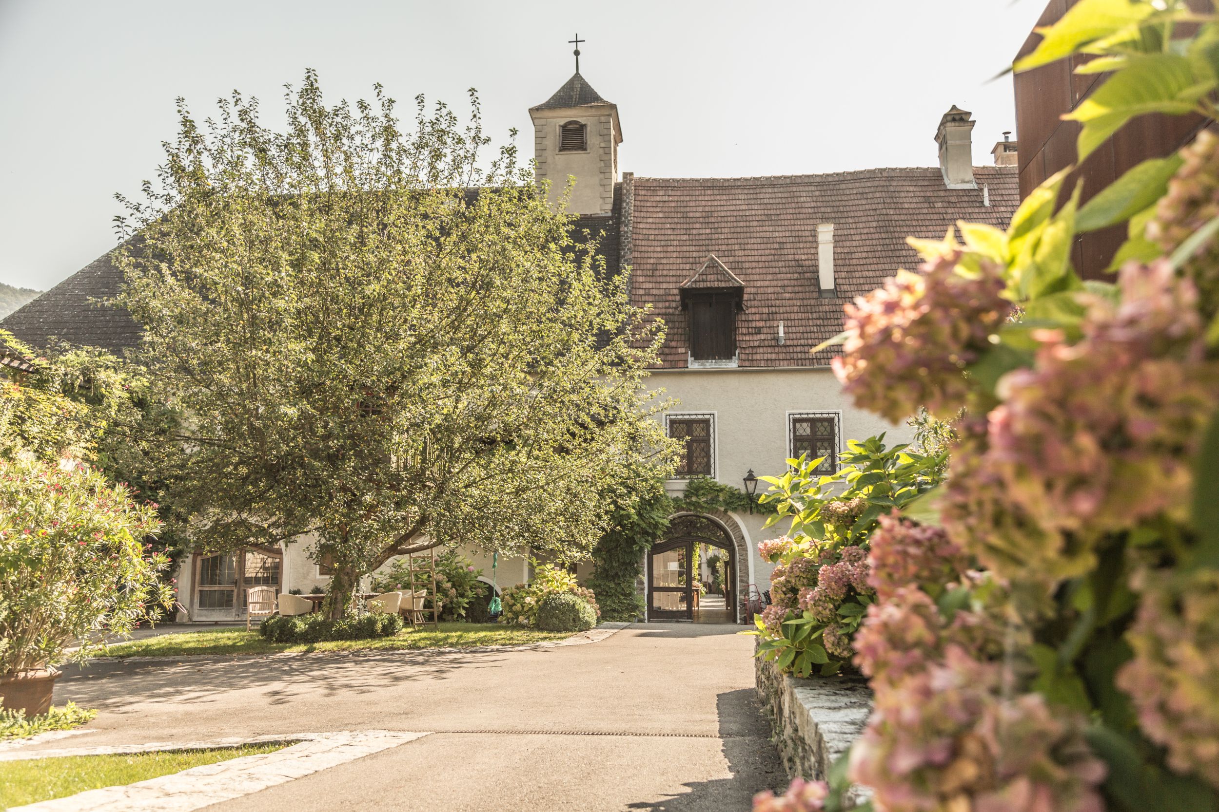 Inner courtyard of the Holzapfel winery with flowering plants and an old building in the background.