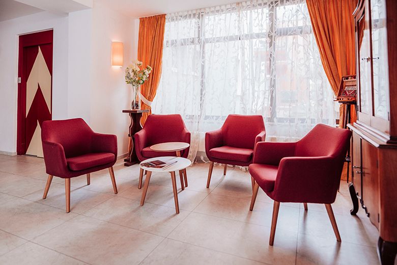 Cozy seating area with red armchairs and a small table in front of a window with curtains.