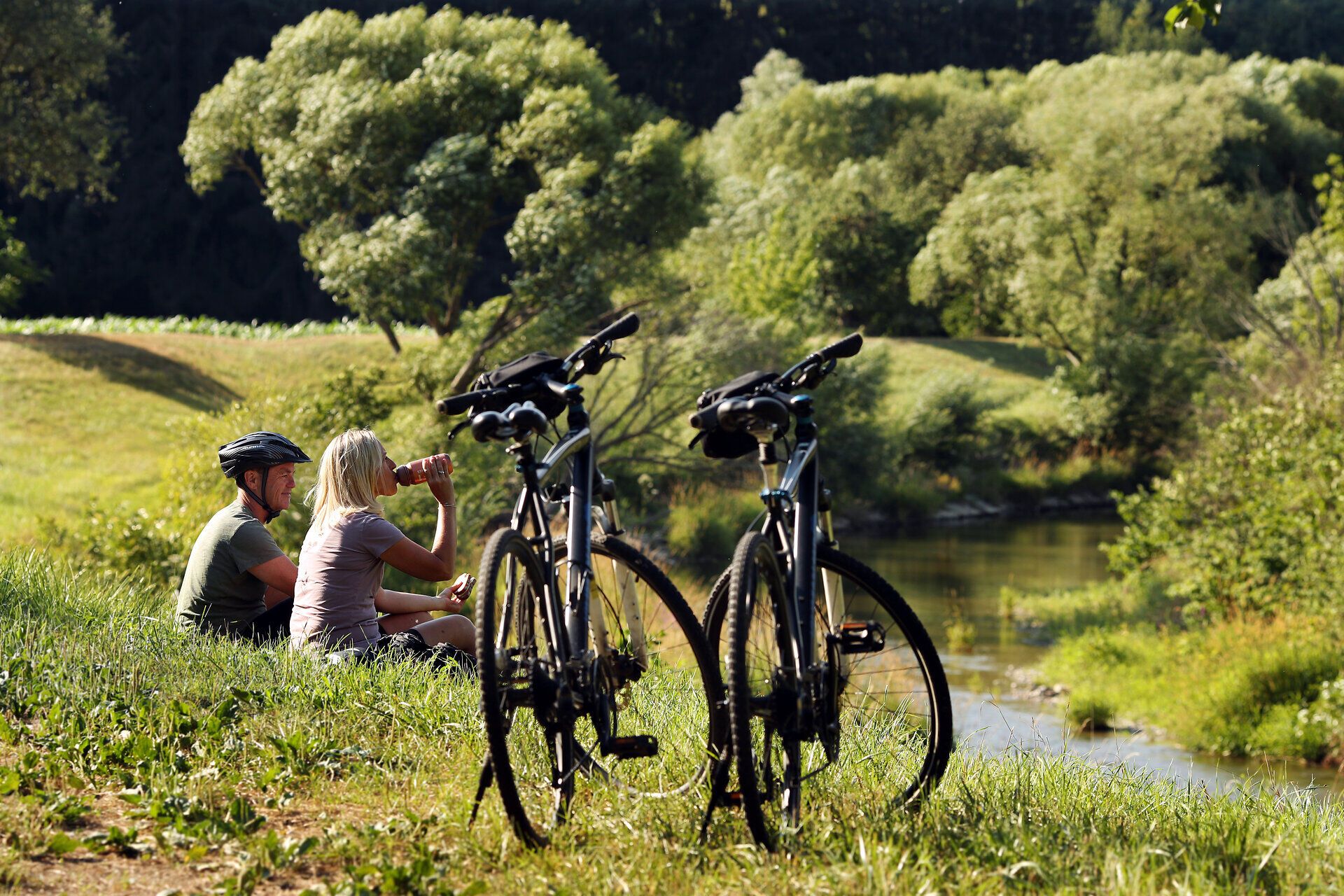 A couple takes a short break from biking along the water.