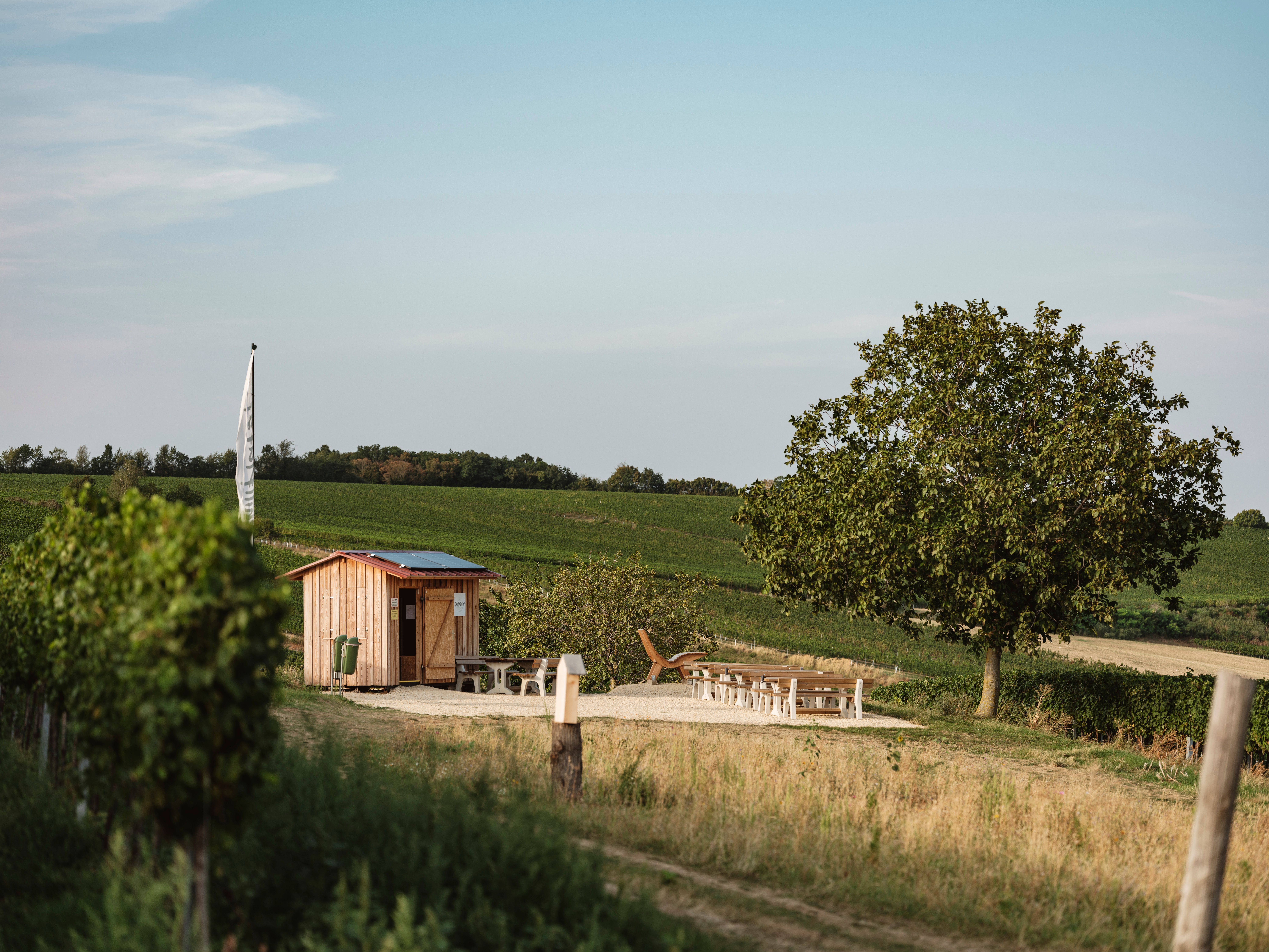 A small wooden hut with seating in a rural landscape.