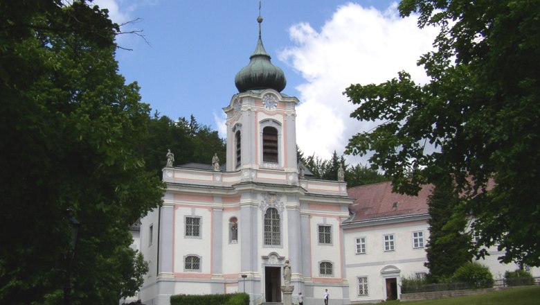 Baroque church on the Mariahilfberg with a green tower and surrounded by trees.