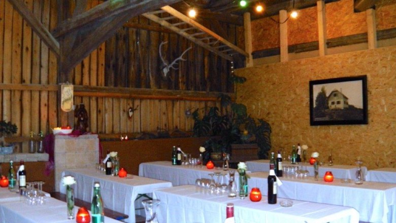 Rustic function room with wooden walls, laid tables and decorations.